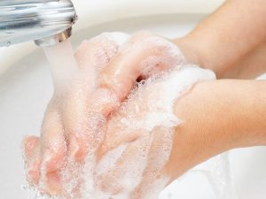 Hände beim Waschen mit Schaumseife unter fließendem Wasser 